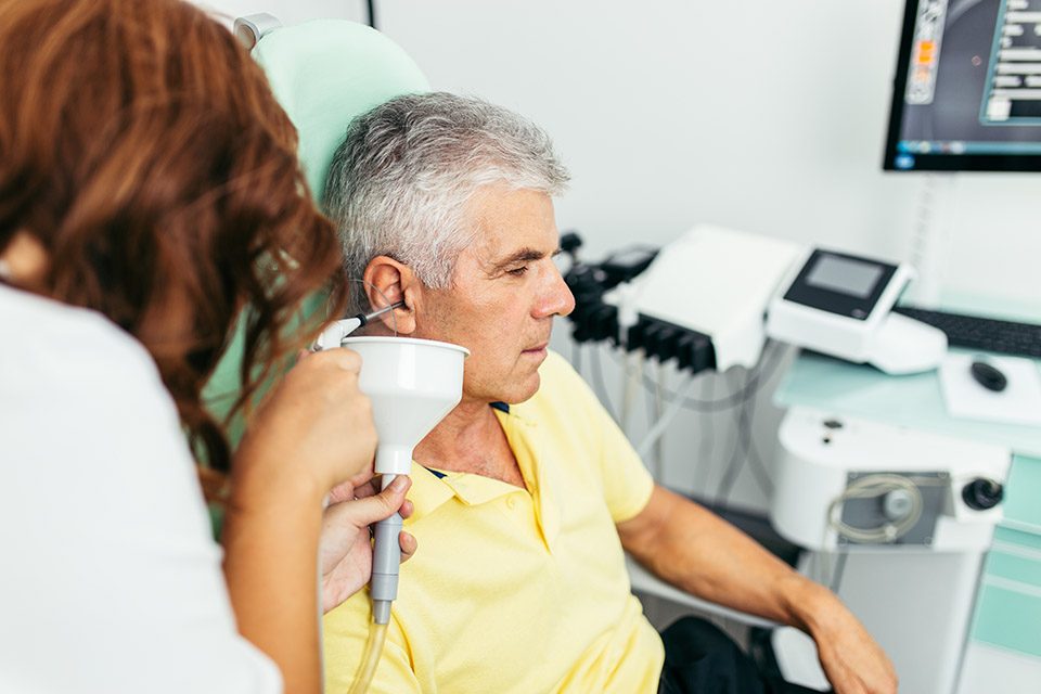 Senior man at medical clinic during ear irrigation and earwax removal