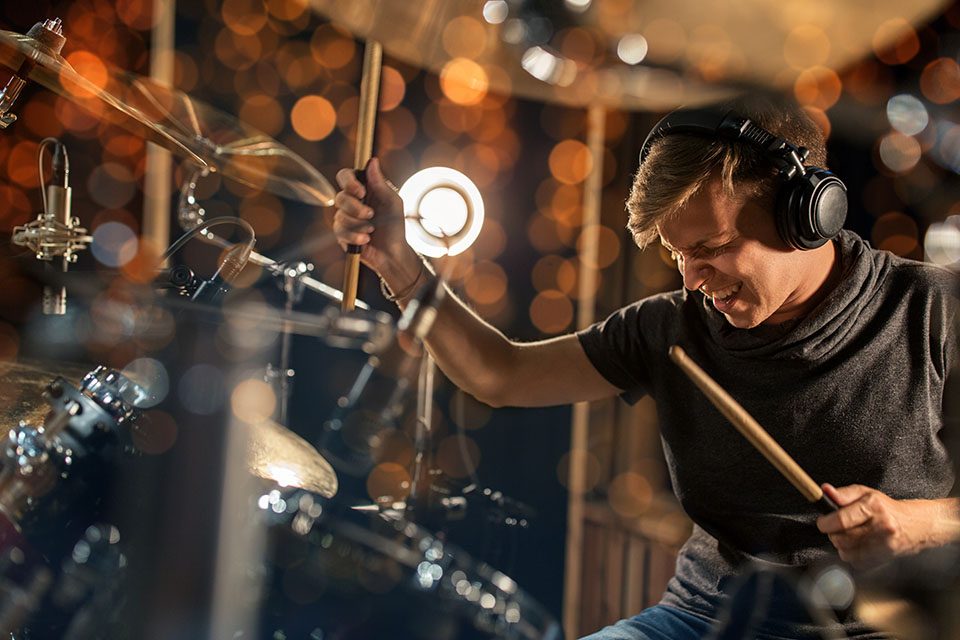 Young man playing drums using hearing protection